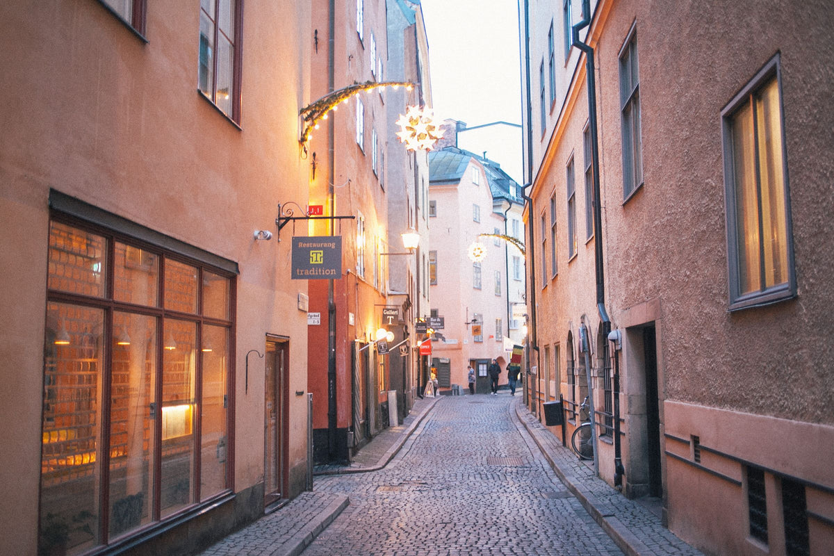 En gränd i Gamla stan i skymningen med tända skyltfönster